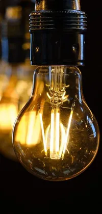 Add a touch of warmth to your phone with our light bulb live wallpaper! This captivating close up shot showcases a glowing warm yellow light bulb hanging from a ceiling, surrounded by thin, glowing devices
