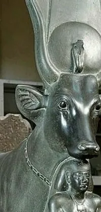 This live wallpaper showcases an intriguing and enigmatic image of a cow statue with a woman situated on its lap, accompanied by a chair and vase located on a table beside them