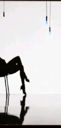 This phone live wallpaper showcases a gorgeous silhouette seated on a sleek chair, exuding an air of sensuality and sophistication