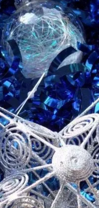 This stunning phone live wallpaper showcases a close-up of a blue crystal Christmas ornament exploding on a table