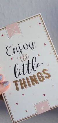 This phone live wallpaper features a metallic card with the quote "enjoy the little things", decorated with shimmering flecks