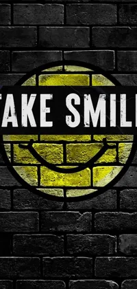 This phone live wallpaper features a striking yellow "fake smile" graffiti sign on a rustic brick wall
