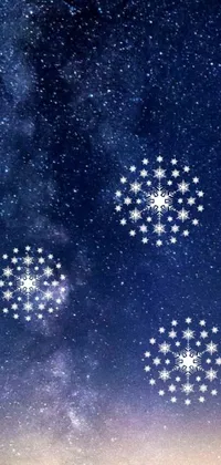 This fascinating live phone wallpaper showcases beautiful snowflakes resting on a snow-covered ground against a starry night sky
