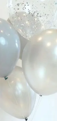 This phone live wallpaper features a cluster of white and silver balloons perched atop a table, floating weightlessly in the air, adding an element of lively motion to your screen