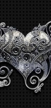 Looking for a bold and intriguing phone live wallpaper? Look no further than this stunning Gothic-inspired design! Against a black backdrop, a gleaming metal object is depicted in 3D detail, shaped like an ornate carved water heart