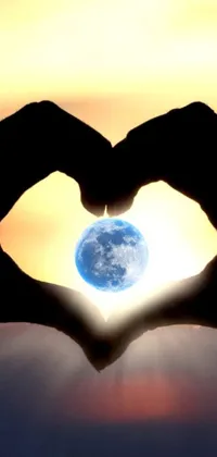 Get mesmerized by this phone live wallpaper that showcases a heart shape made from hands against two pure moons and a blue marble, while the background shapes of cryptocurrency show the love for technology