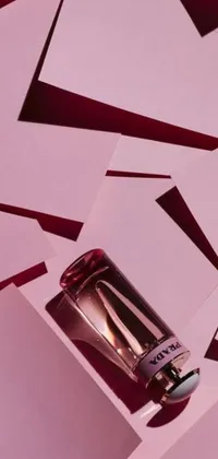 This live wallpaper features a pink and red themed design with a Prada perfume bottle situated on top of a pile of papers