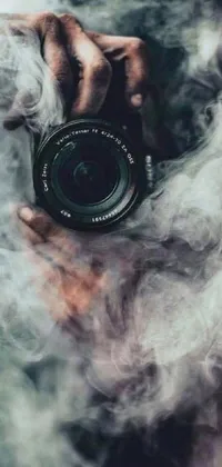 This phone live wallpaper showcases a captivating scene of someone capturing a moment with their camera, accompanied by swirly smoke, marijuana photography, and fantastical elements