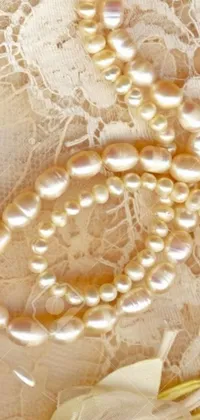 This phone live wallpaper features a stunning pearl necklace displayed on top of an intricate lace tablecloth