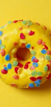 Looking for a fun and vibrant live wallpaper for your phone? Check out this yellow surface where a delicious donut with sprinkles is displayed