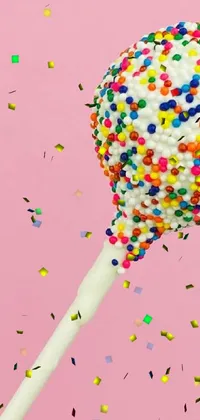 This delightful live phone wallpaper showcases an image of a mouth-watering lollipop on a stick, coated in colorful sprinkles