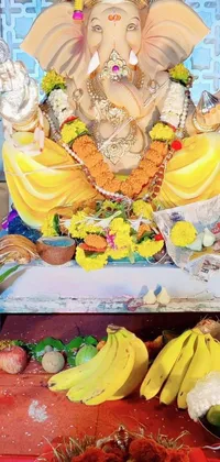 This live phone wallpaper features an elephant statue on a floral and fruity table