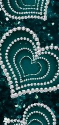Add elegance and romance to your phone with this stunning live wallpaper! Featuring three hearts crafted from pearls on a beautiful blue background, this wallpaper is a true work of art
