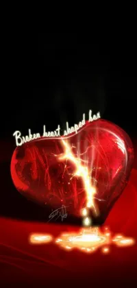 Introducing a stunning live wallpaper for your phone! This visually striking wallpaper features a broken heart sitting on a red table that is highlighted with beautiful graphics and broken lights