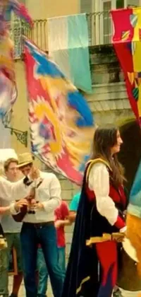 This phone live wallpaper captures a bustling, Renaissance-era street scene, with draped cloth banners and a lively group of people performing a music video
