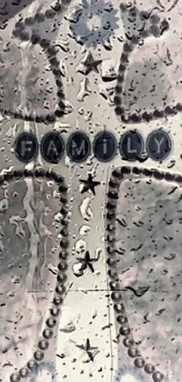 This live phone wallpaper features a diverse collection of high-quality close-up images, including a rain-covered window with a cross, an album cover by Anna Findlay, graffiti art, a happy family, monochromatic airbrush painting, water droplets, and pressed penny art