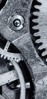 This live phone wallpaper displays a captivating black and white photograph of gears shot in macro detail