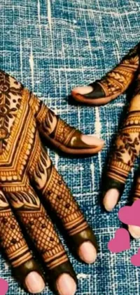 This phone live wallpaper showcases intricate henna designs on a pair of hands set against a polished wood background