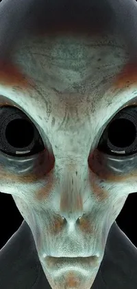 This live wallpaper for phones features a close-up of an alien face, rendered digitally, with a pale, round face, gray anthropomorphic features, large, black almond-shaped eyes, and a small, thin-lipped mouth, set against a black background