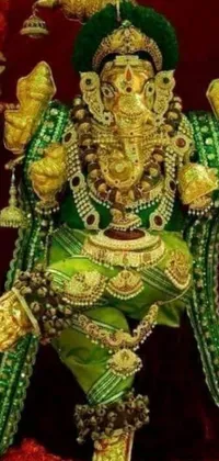 This phone wallpaper showcases a close-up of a luxurious statue of an Indian god, featuring ornate green and gold attire and glistening gold jewelry
