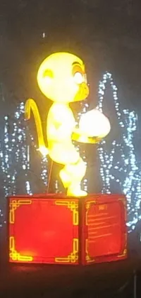 This colorful live wallpaper features an intricately designed monkey statue sitting on a box atop an illuminated stage