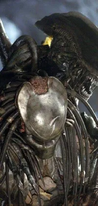 This live wallpaper features a close-up view of a shiny-breastplated animatronic alien statue with glowing sidereal eyes, standing atop an ornately-carved pedestal against a backdrop of dark, starry space