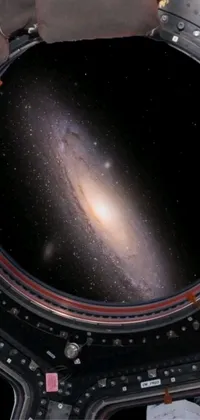 This phone live wallpaper captures the stunning view of a galaxy framed by a space station's dome