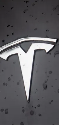 This phone live wallpaper features a close-up view of a Tesla logo on a car