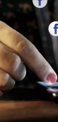 This phone live wallpaper shows a close-up shot of a hand holding a cell phone, with a Facebook post displayed on the screen