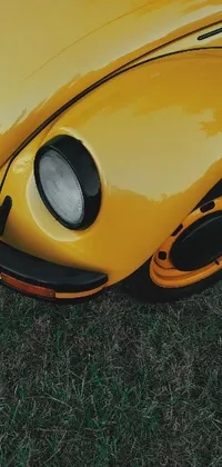 This sensational phone live wallpaper features a remarkable yellow vintage beetle parked on lush green fields