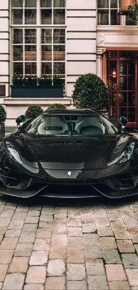 This phone live wallpaper depicts a black sports car parked in front of a grand building
