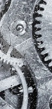 This phone live wallpaper displays a black and white photograph of gears in macro, providing a detailed representation of the metal textures