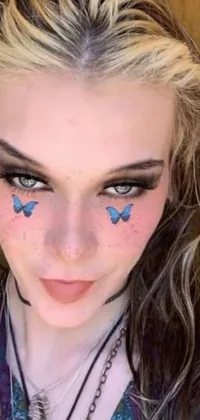 This live wallpaper for your phone features an enchanting woman with delicate blue butterfly face paint and starry tattoos on her arms