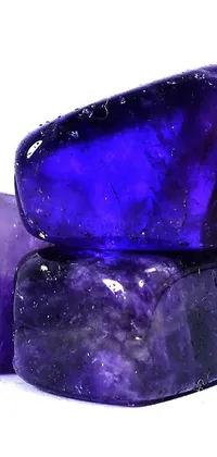 Elevate your phone's appearance with this captivating live wallpaper featuring a striking image of two lustrous, purple rocks stacked upon one another