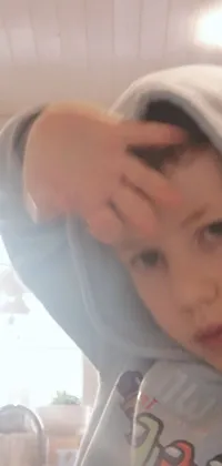 Looking for a heartwarming live wallpaper for your phone that radiates coziness and simplicity? Our close-up depiction of a child, wearing a hoodie and wrapped in robes, is the perfect choice