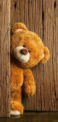 This live wallpaper showcases a cute, brown teddy bear leaning against a wooden wall with a trendy picture above