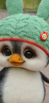 This phone live wallpaper showcases a realistic close-up image of a cute stuffed penguin donning a hat