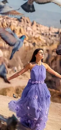This phone live wallpaper depicts a stunning scene of a woman wearing a purple dress in the company of pigeons