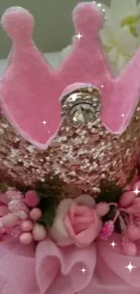 This stunning phone live wallpaper showcases a detailed crown on a table, dressed up with a pink tutu