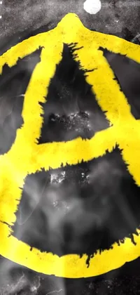 This dynamic phone live wallpaper features a striking yellow anarchy symbol painted on a building, displayed in an edgy punk rock album art style