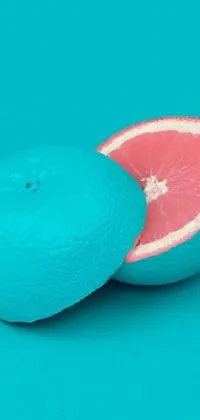 This colorful live wallpaper features stunning hyper-realistic artwork of a perfectly sliced grapefruit placed on a blue surface