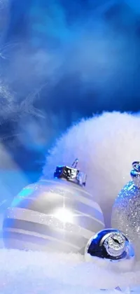 This live wallpaper features two Christmas balls sitting on a snow-covered ground with a dramatic blue and white lighting effect by Marie Bashkirtseff