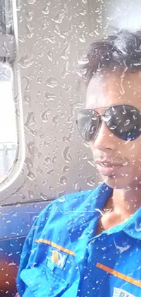 This live wallpaper for your phone features a man wearing sunglasses and a blue shirt sitting on a train, gazing out the window
