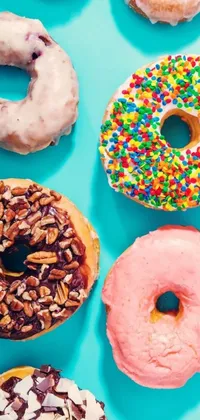 Looking for a colorful and fun live wallpaper for your phone? Check out this eye-catching option featuring a variety of vibrantly decorated doughnuts arranged on a bright blue backdrop - perfect for adding a lively pop of color to your screen