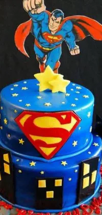 This phone live wallpaper features a detailed and vibrant Superman cake on display atop a sturdy table against a dark nighttime sky