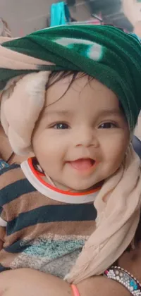 This live wallpaper shows a sweet depiction of a woman cuddling a baby sporting a green hat against a hurufiyya-inspired background