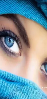This alluring phone live wallpaper showcases a vivid close-up of a blue-eyed woman, wearing a striking burqa