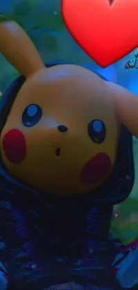This phone live wallpaper features a close-up view of a plush Pikachu toy holding a heart in the foreground, set against a dreamy forest background