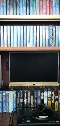 The wooden shelf phone live wallpaper features a vintage computer monitor sitting atop a wooden shelf surrounded by tomes, VCR tape, and bluray disks