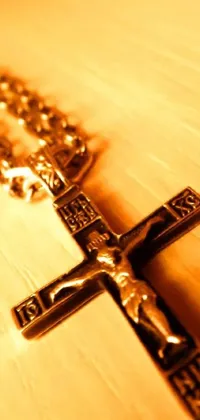 This live phone wallpaper features a stunning golden cross set upon a wooden table